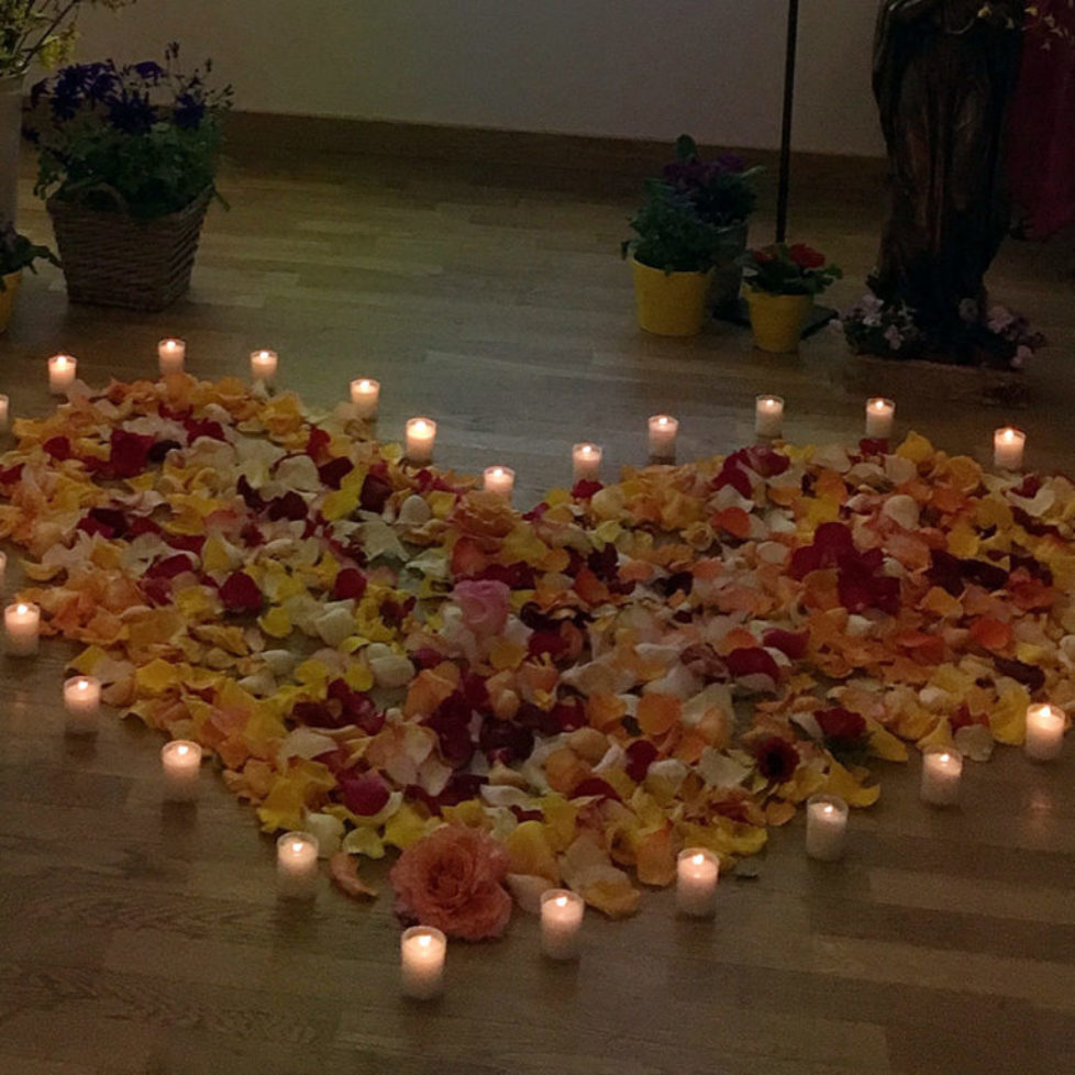 Herz aus Blütenblättern mit Kerzen