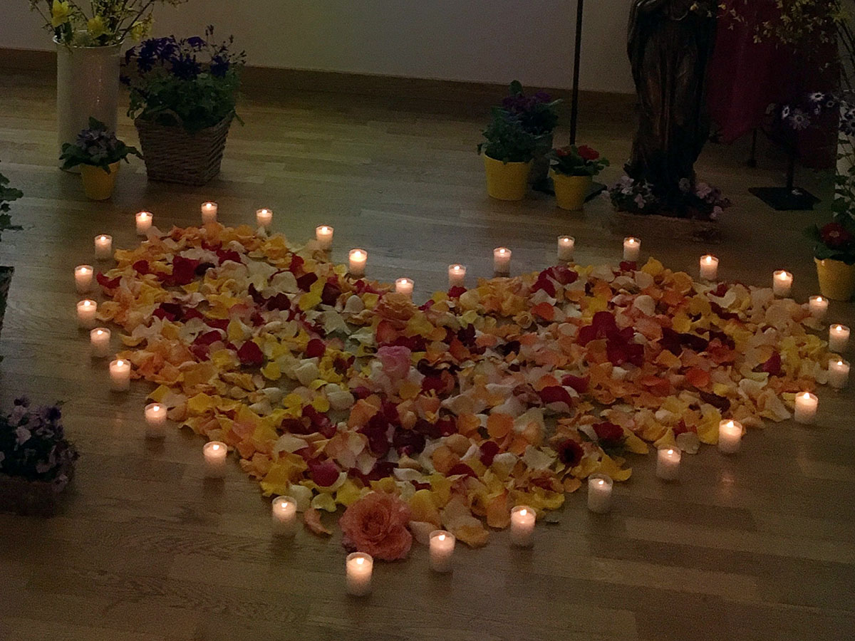 Herz aus Blütenblättern mit Kerzen